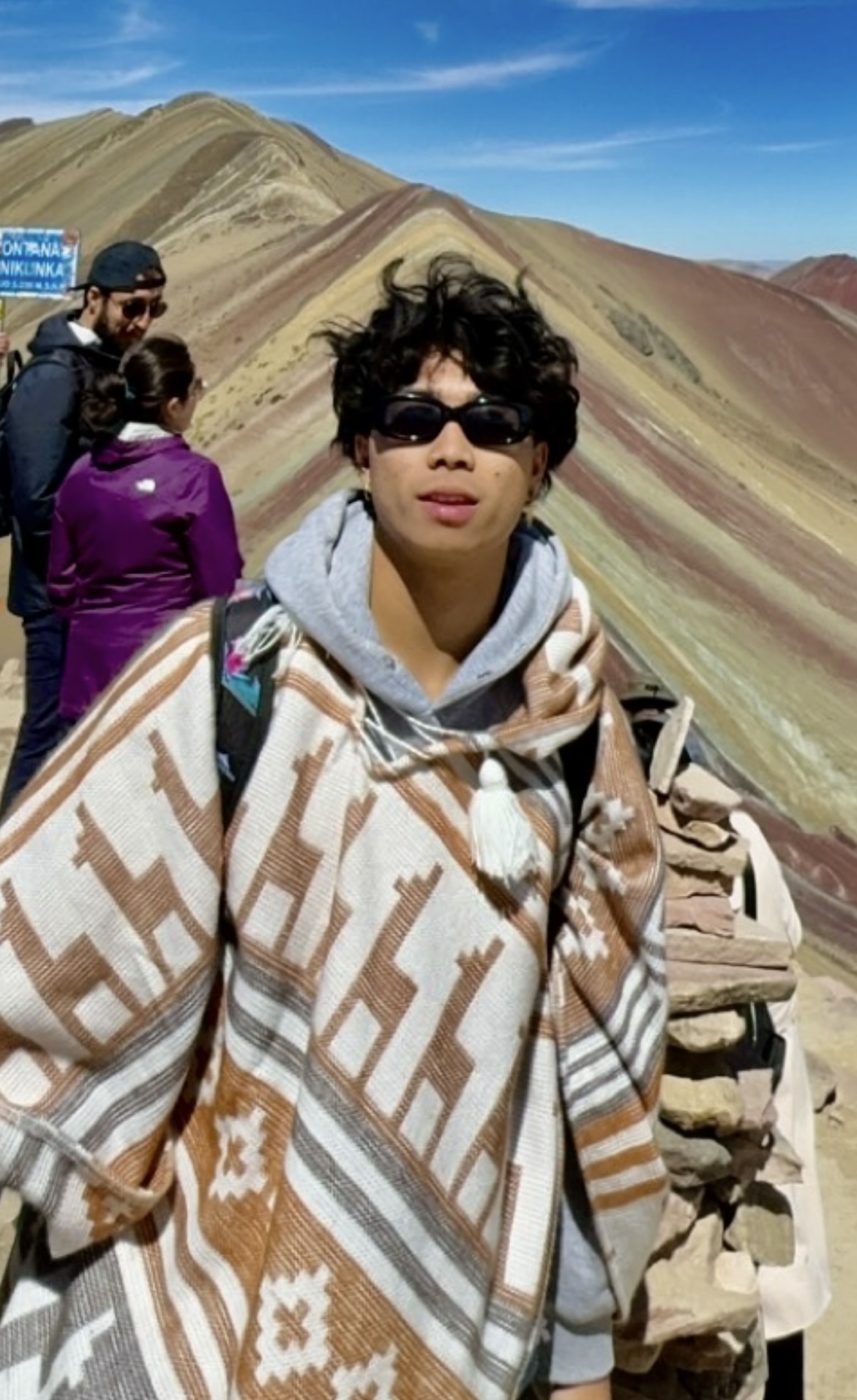 Shawn in an oversized tribal poncho walking on the ridge of mountainous sand dunes in a far away land.
