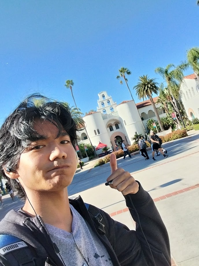Aiden with a thumbs up in front of Montezuma Hall