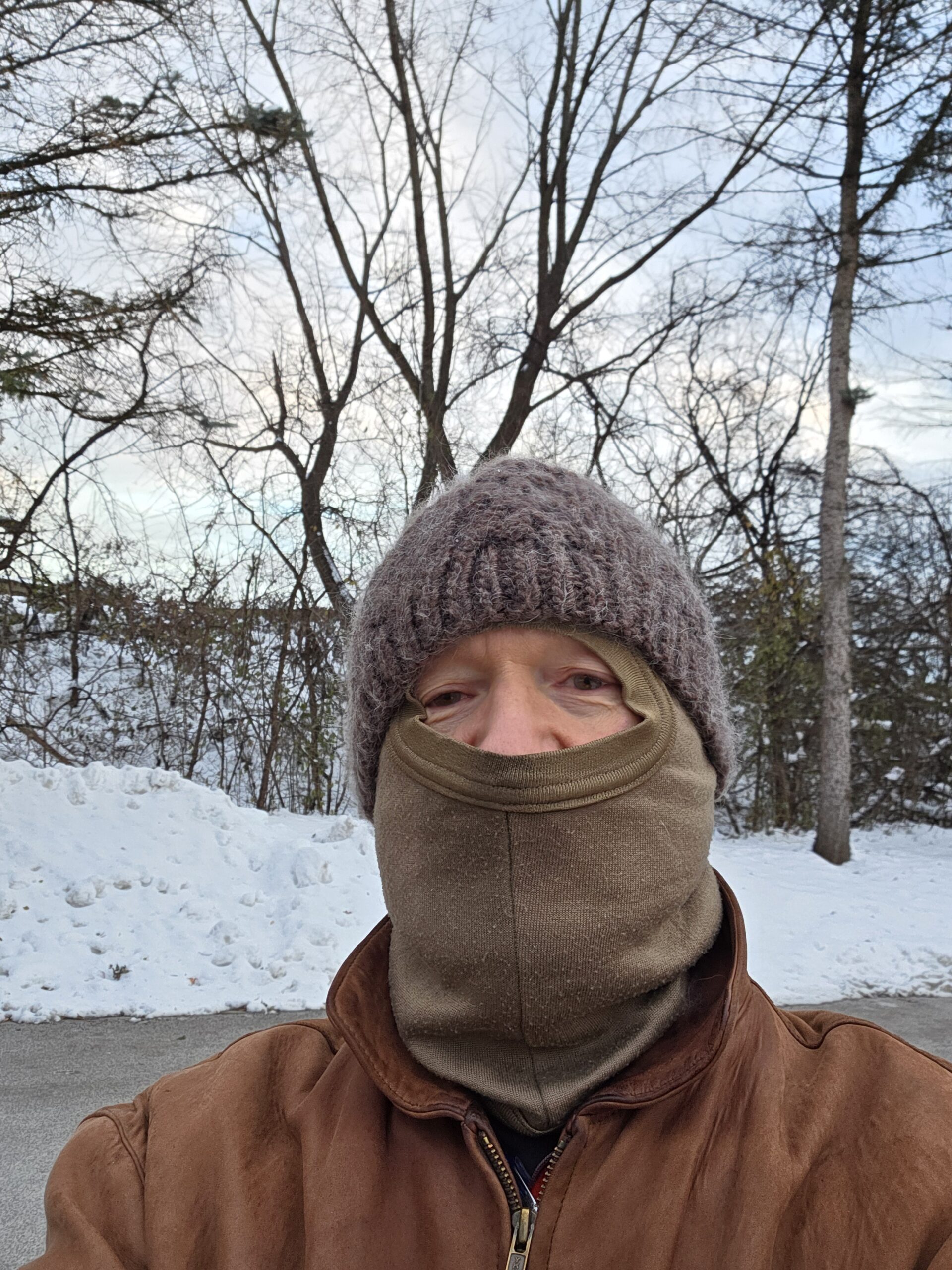Dr. K is outside in the snow with a beanie and a balaclava.